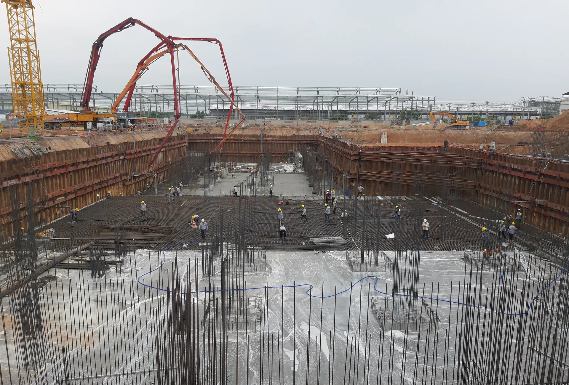 Excavators and a concrete pump at work on an industrial plant foundation